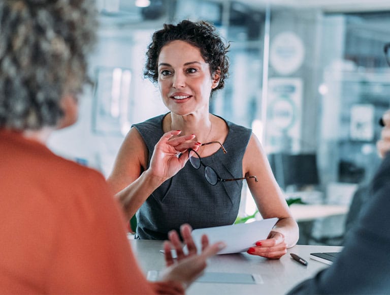 Woman discussing business ideas with colleagues in an office meeting.